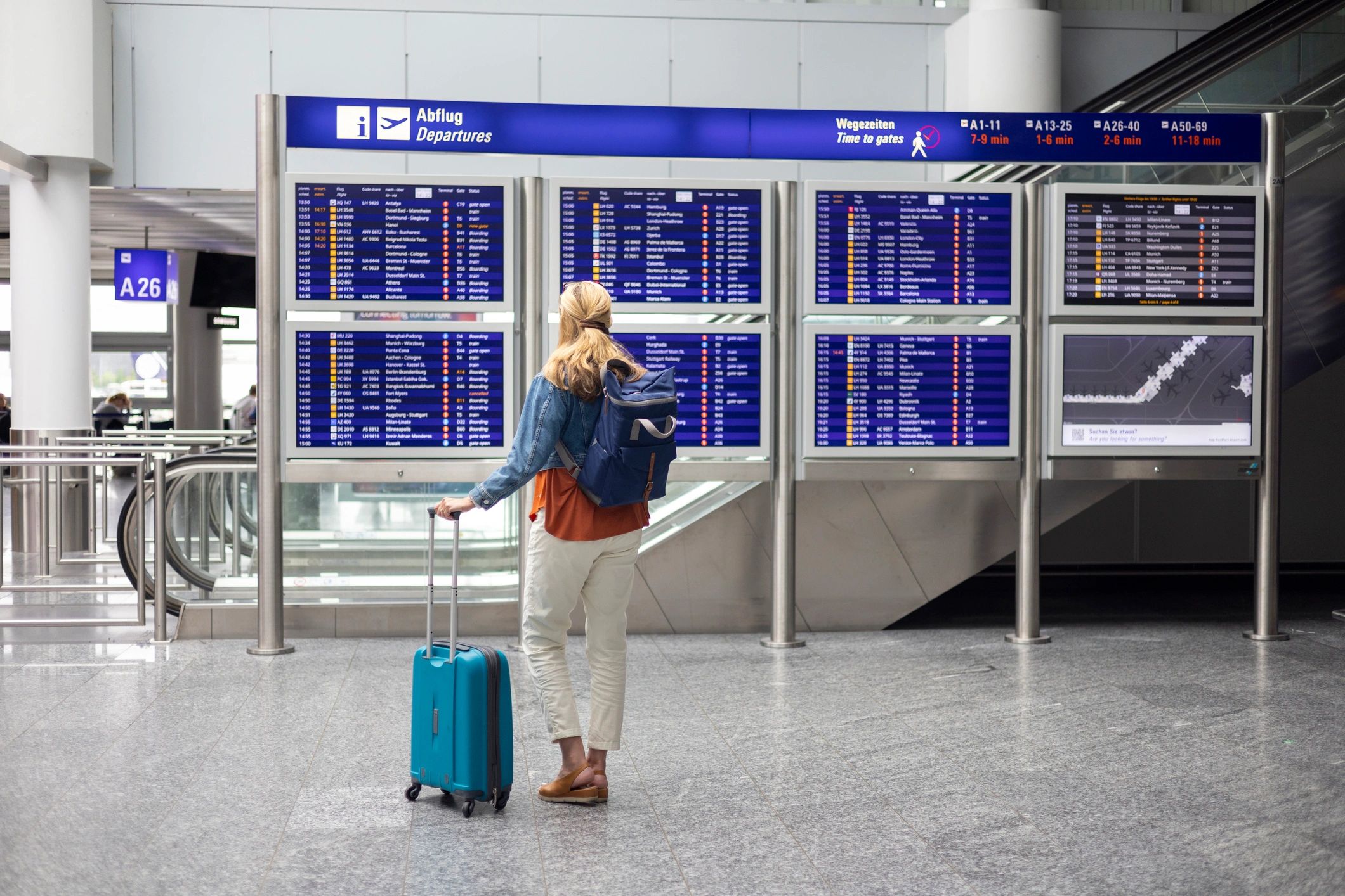 Traveler checking airport departure board with suitcase
